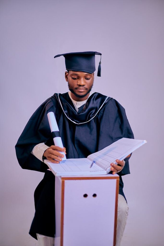 Young graduate wearing cap and gown holding a diploma.