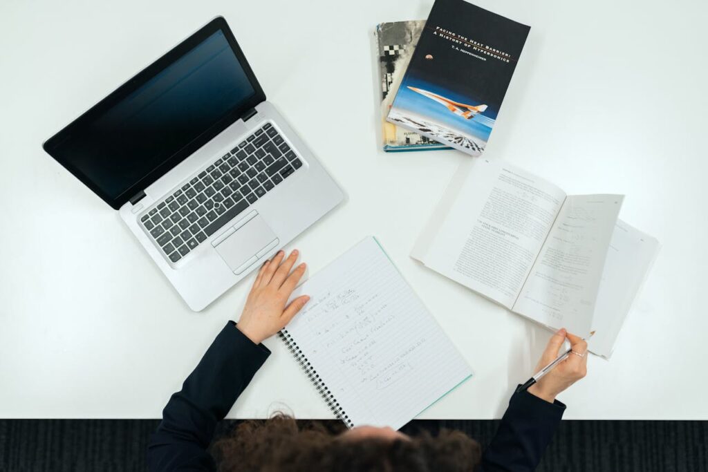 Top view of a work desk with laptop, books, and notes showcasing productivity.